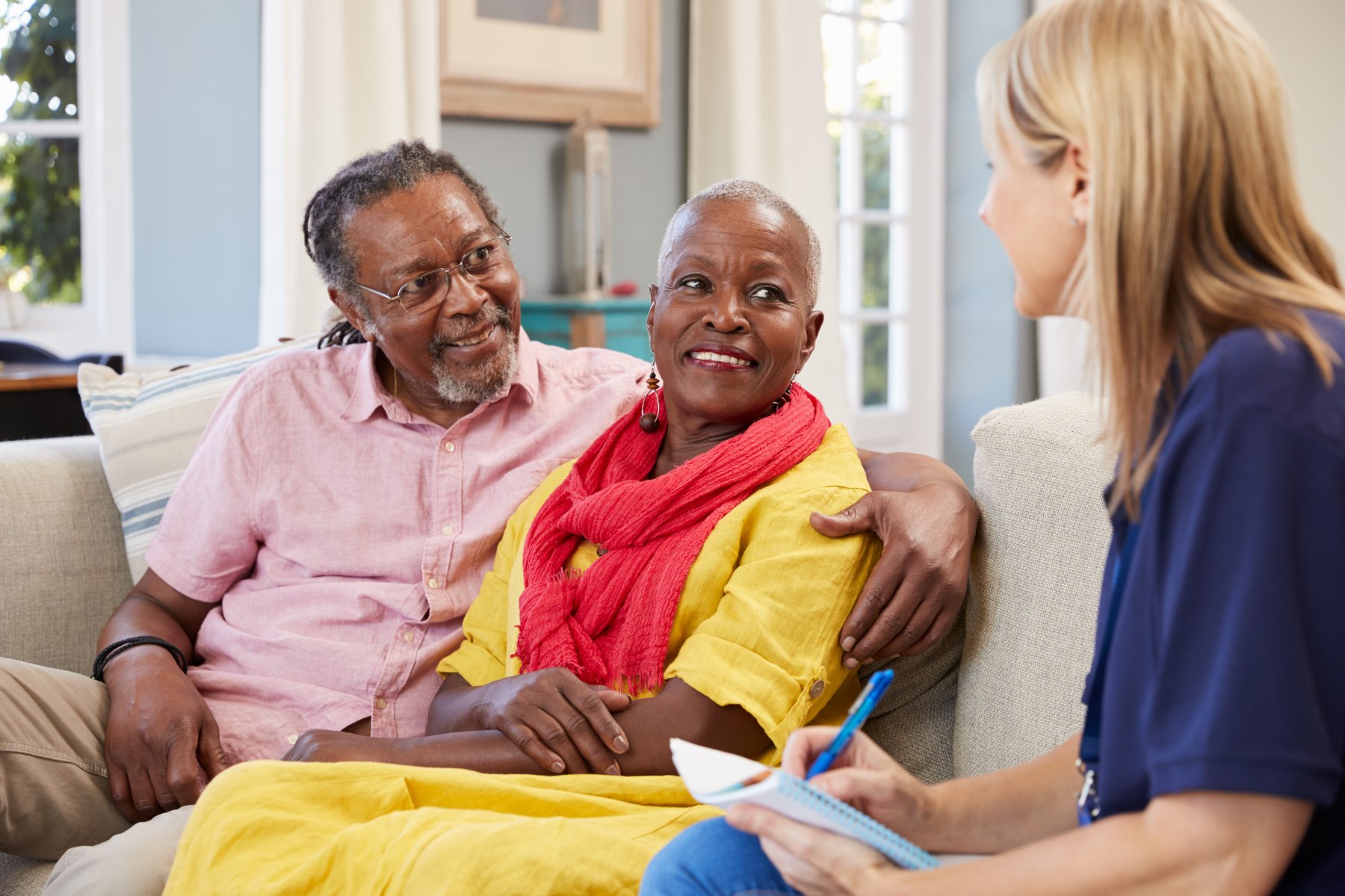 A caregiver meeting with a client couple in their living room