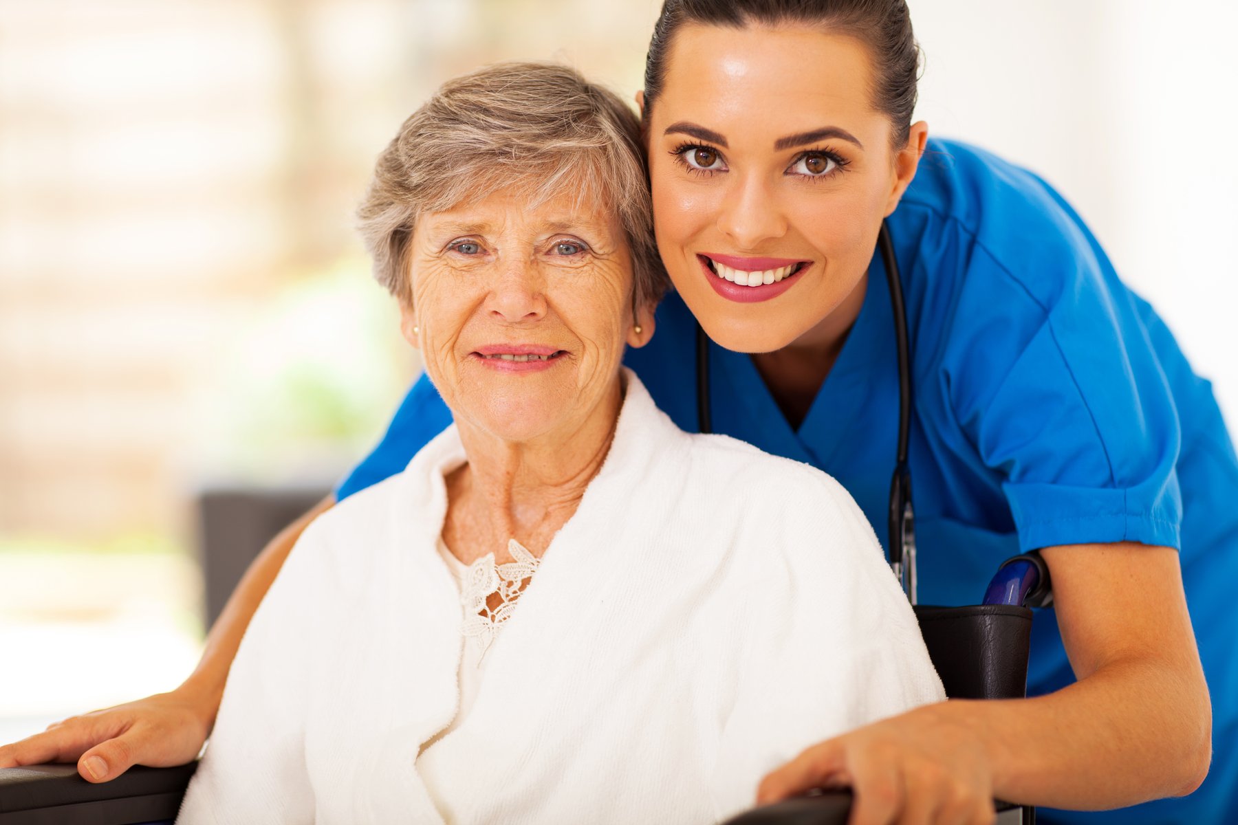 A caregiver embracing an elderly client, both smiling