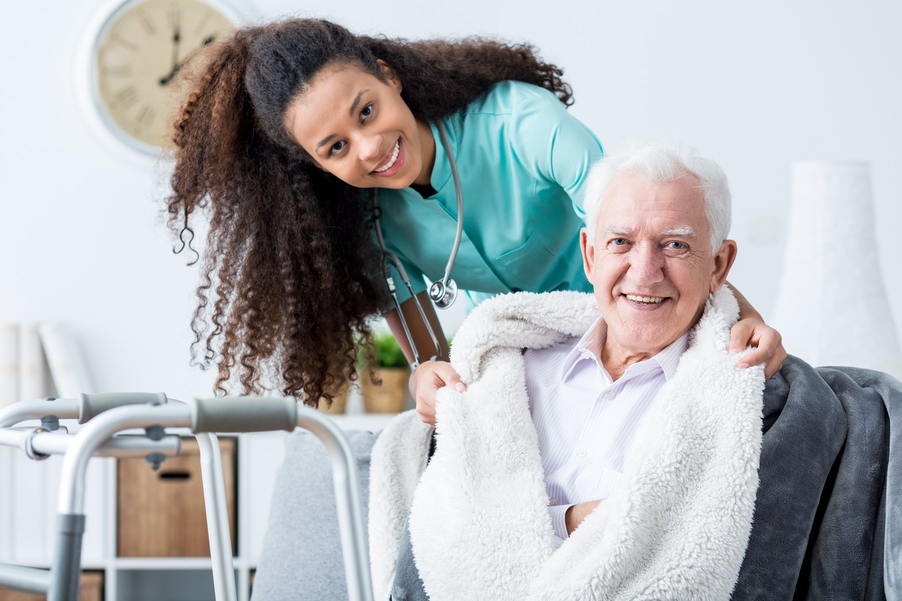 A caregiver wrapping a blanket around a senior client